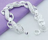 Silver bracelet on a light gray background with a purple fabric underneath