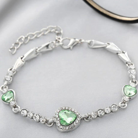 Silver bracelet with green gemstones on a light gray background
