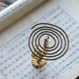 Coiled incense stick on a gold holder over an open book with text.