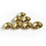 Set of seven small brass bowls on a white background