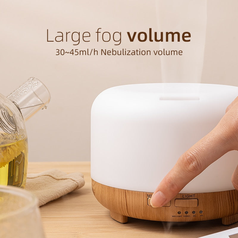 White and wooden diffuser on a table with a hand pressing a button, and text about large fog volume.