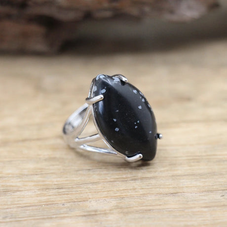 Silver ring with a large black stone on a wooden surface