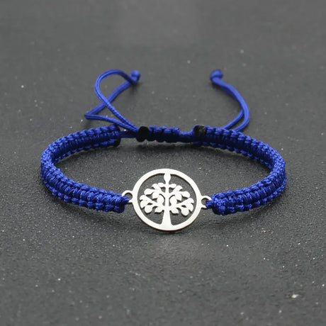 Blue braided bracelet with a silver tree-of-life charm on a dark gray background