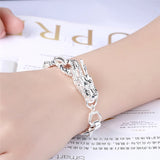 Silver bracelet on a wrist with a blurred magazine background
