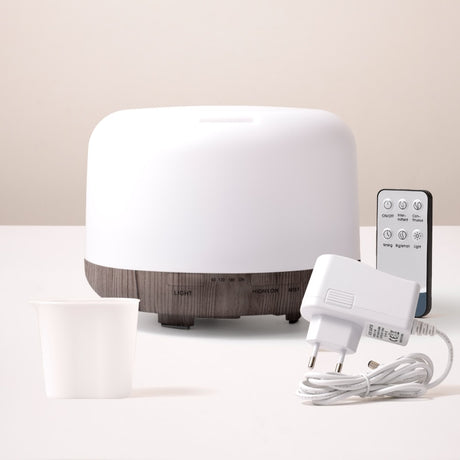 White diffuser with wooden base, remote control, and power adapter on a light background