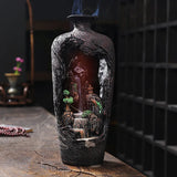 Decorative bottle with a miniature landscape inside, featuring trees and a waterfall.