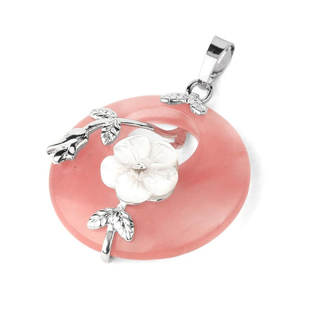 Jewelry pendant with pink stone and silver floral design on a white background