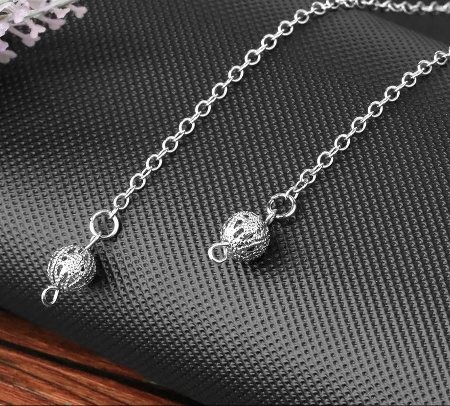 Silver chain necklace with spherical pendants on a textured surface