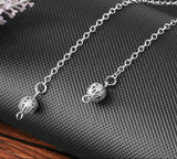 Silver chain necklace with spherical pendants on a textured surface