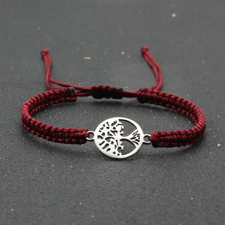 Red braided bracelet with a silver tree of life charm on a dark background