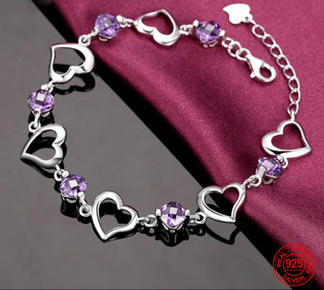 Silver bracelet with heart-shaped links and purple beads on a red fabric background, featuring the brand 'ZDADAN'.