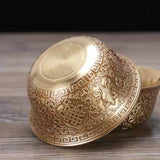 Decorative gold bowl with intricate patterns on a wooden surface