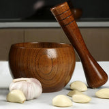 Wooden mortar and pestle with garlic cloves on a neutral background