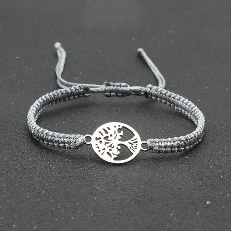 Gray braided bracelet with a silver tree of life charm on a dark background