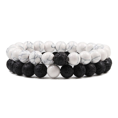 Two bracelets with white marbled beads and black volcanic beads on a white background