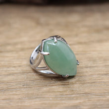 Silver ring with a green stone on a wooden surface