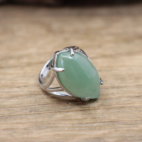 Silver ring with a green stone on a wooden surface