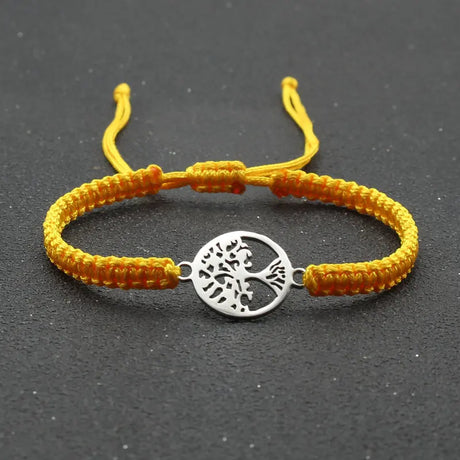 Yellow bracelet with a silver tree of life charm on a black background