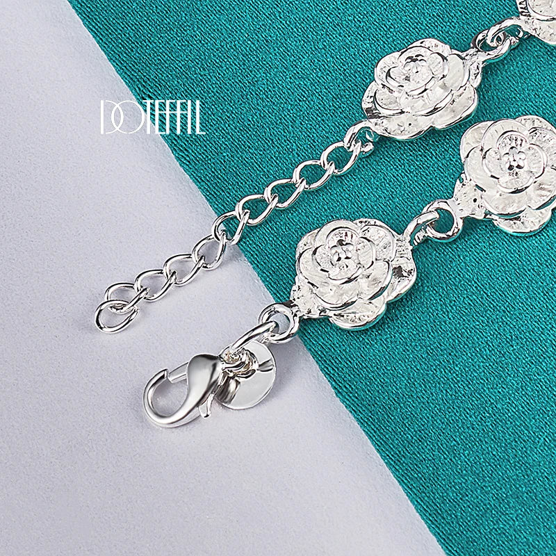 Silver bracelet with rose-shaped charms on a teal and gray background