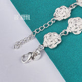 Silver bracelet with rose-shaped charms on a teal and gray background