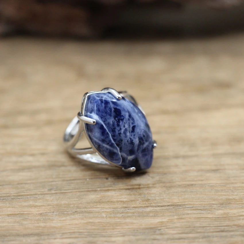 Silver ring with a large blue stone on a wooden surface