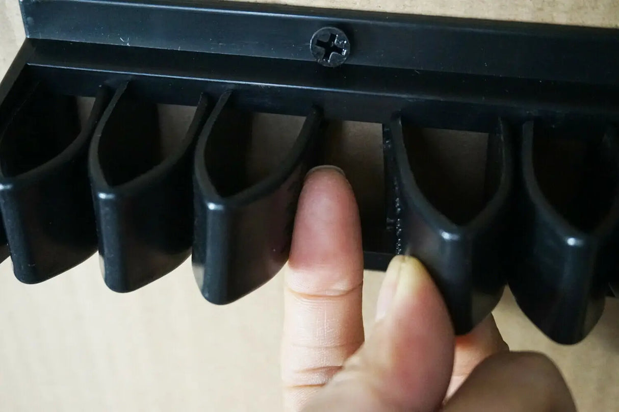 Black plastic tool with multiple slots held by a hand