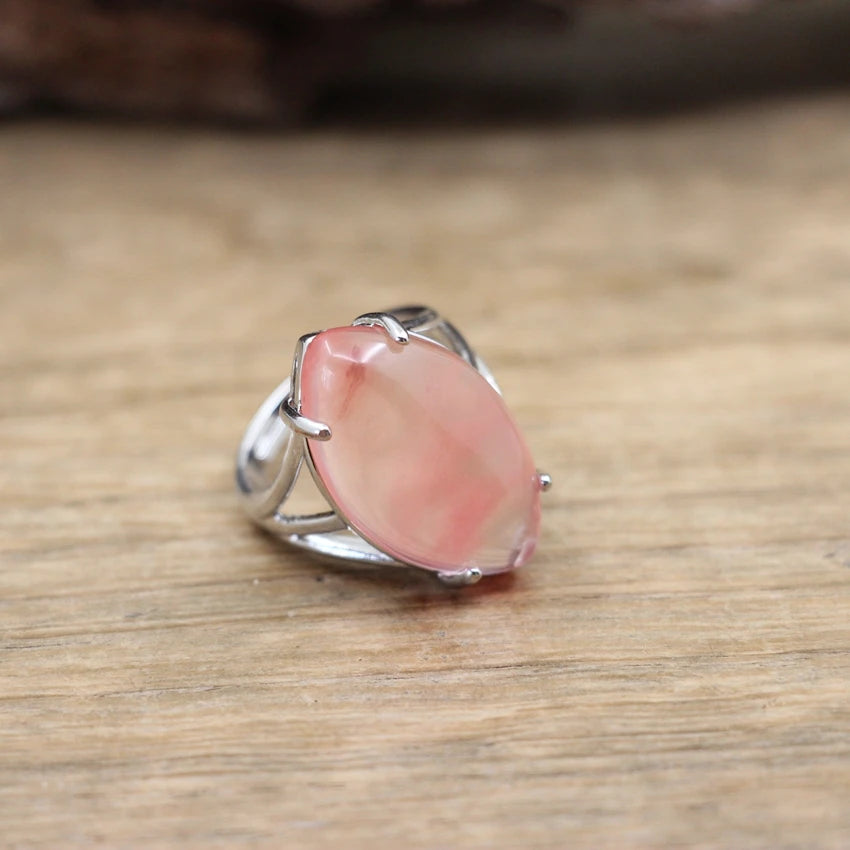 Silver ring with a pink stone on a wooden surface