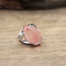 Silver ring with a pink stone on a wooden surface