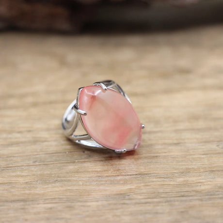 Silver ring with a pink stone on a wooden surface