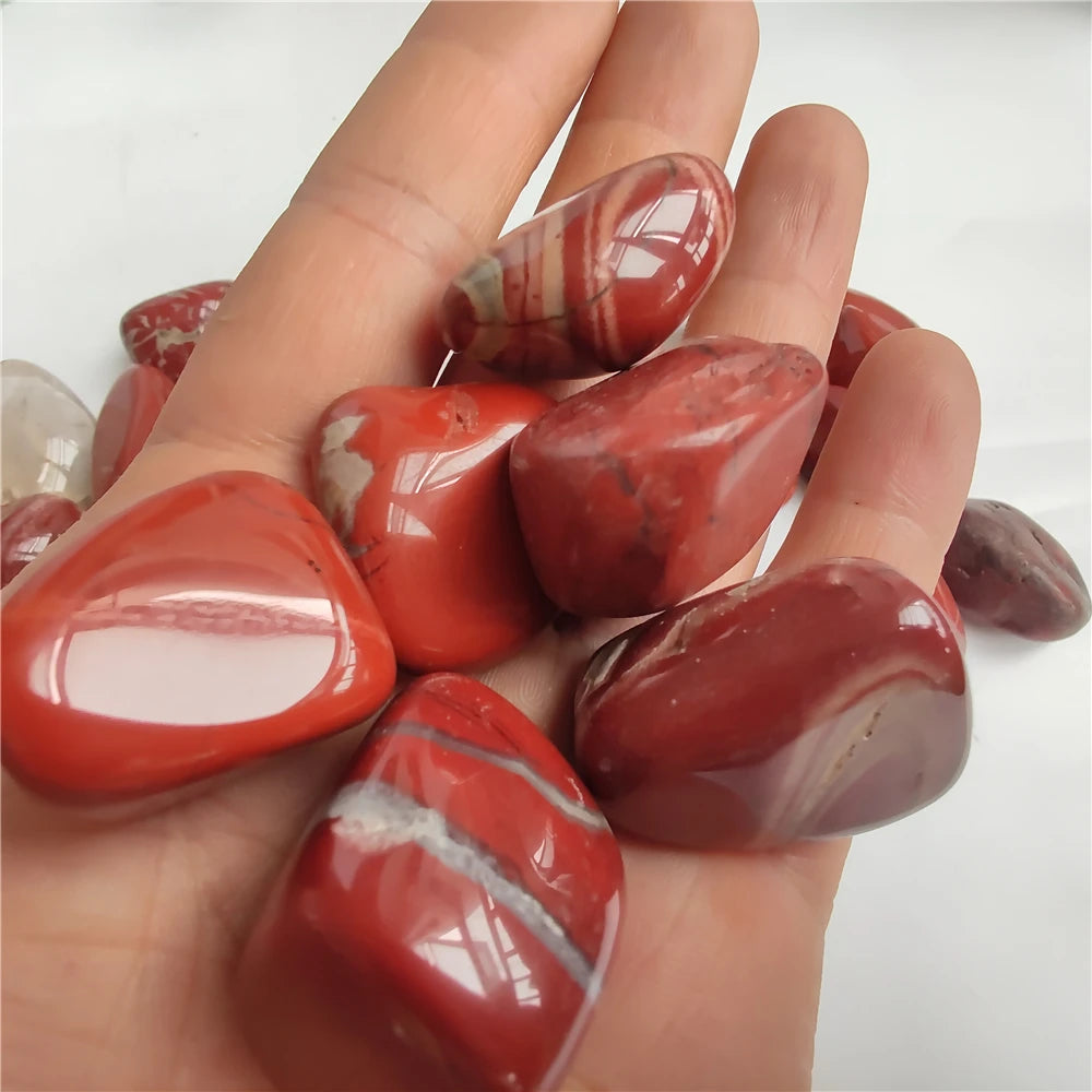 Hand holding red marbled stones against a white background