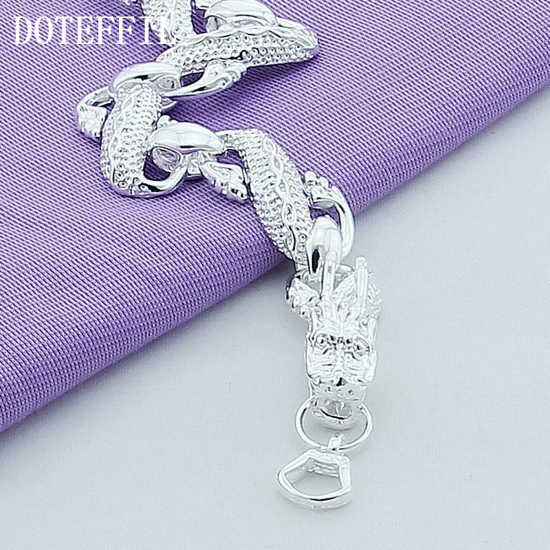 Silver bracelet with dragon design on a purple fabric background