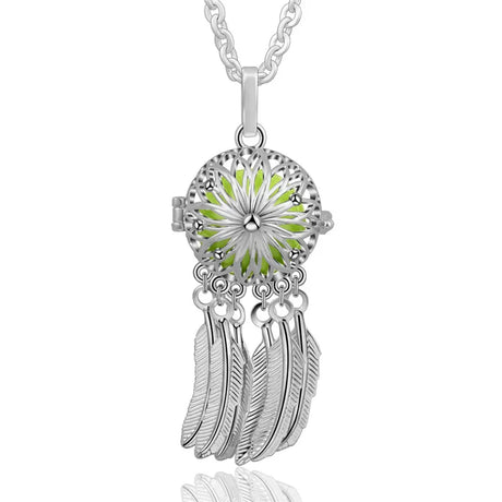 Silver dreamcatcher pendant with green center and feathers on a white background