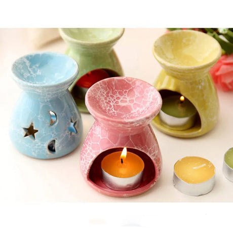 Colorful ceramic wax warmers with candles on a white surface
