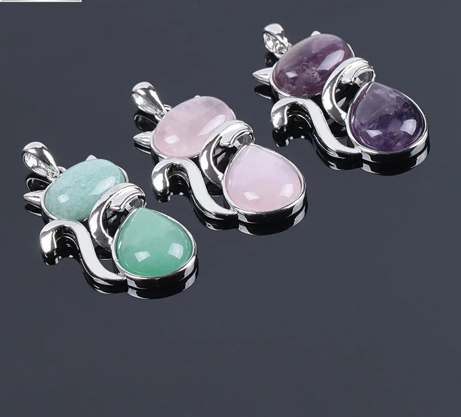 Three gemstone pendants on a reflective surface with a dark background