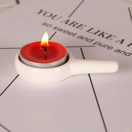 Red candle in a white holder on a textured surface with text
