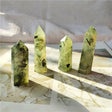 Four green crystal points on a marble surface with a white towel in the background