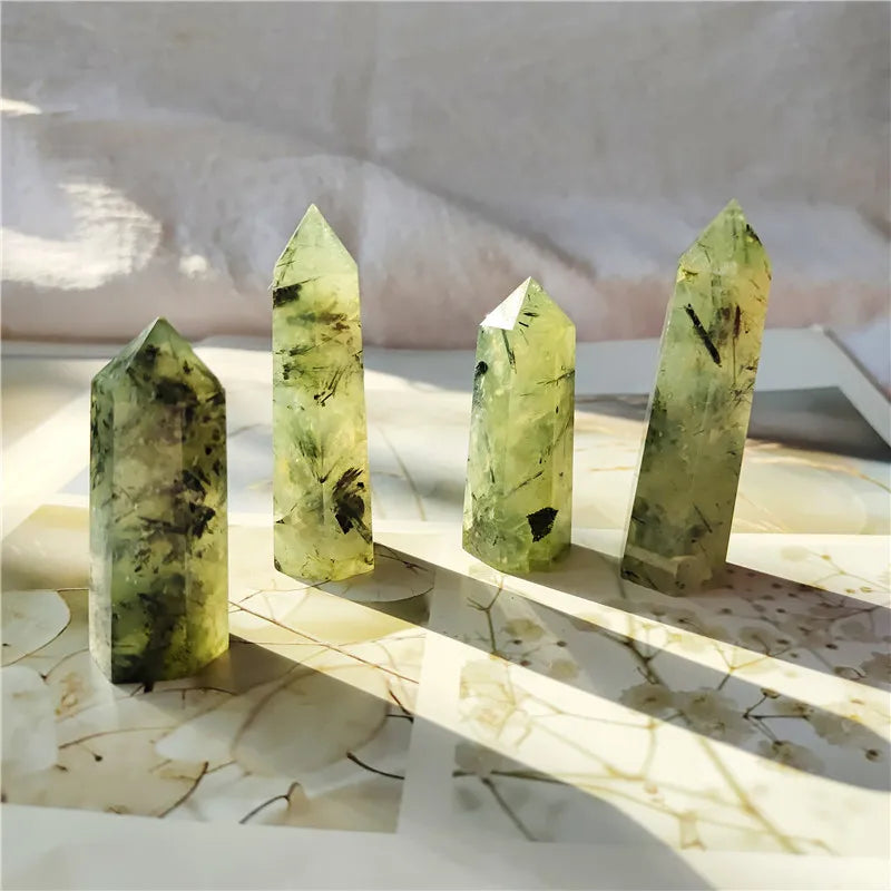Four green crystal points on a marble surface with a white towel in the background