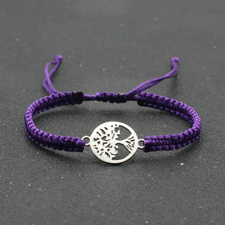 Purple bracelet with a silver tree-of-life charm on a dark gray background
