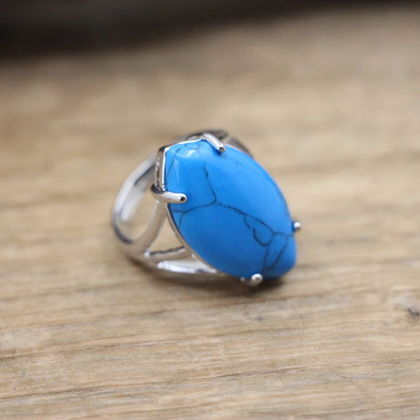 Silver ring with a blue stone on a wooden surface