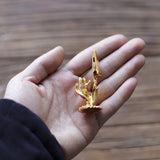 Gold figurine of a hand holding a heart on a person's palm against a wooden background