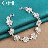 Silver rose bracelet on a teal and beige fabric background with 'DOVEFIL' branding.