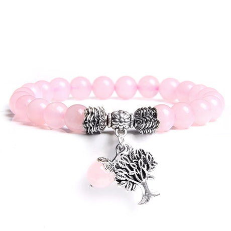 Pink beaded bracelet with silver tree charm on a white background