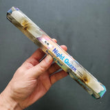 Hand holding a 'Night Queen' incense stick with a gray background