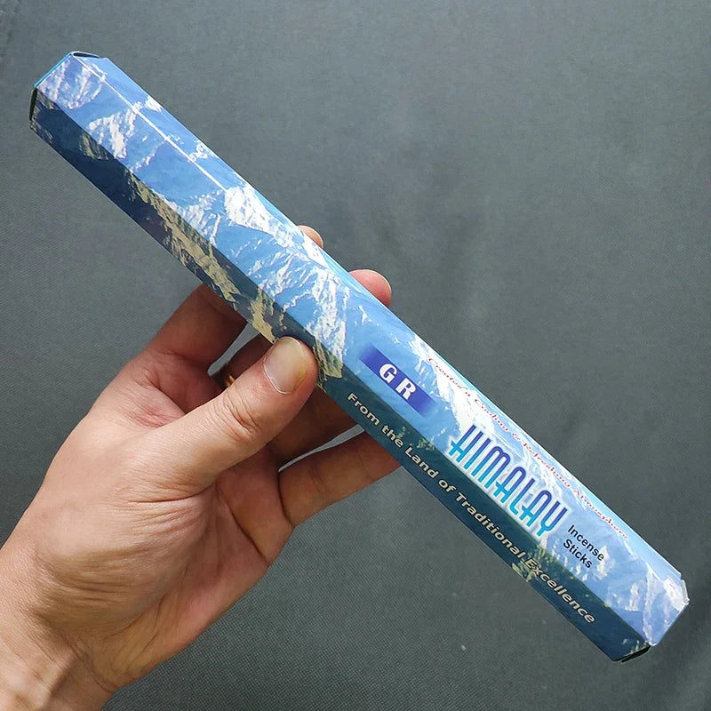 Hand holding a blue Himalayan salt stick against a gray background