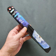 Hand holding a incense box with a colorful design on a gray background