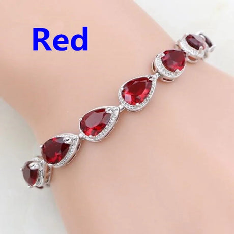 Red teardrop-shaped gemstone bracelet on a wrist with a plain background