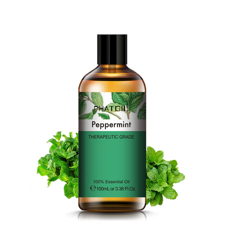 Bottle of peppermint essential oil with green leaves on a white background
