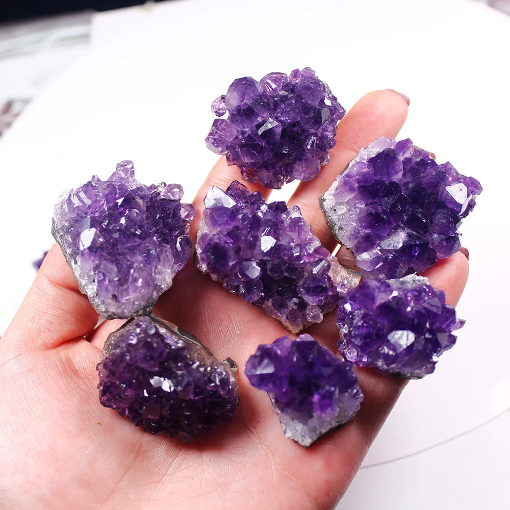Hand holding purple amethyst crystals against a blurred background