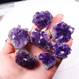 Hand holding purple amethyst crystals against a blurred background