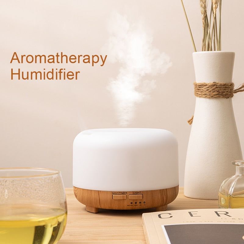 Aromatherapy humidifier on a table with a glass of liquid and a vase in the background.